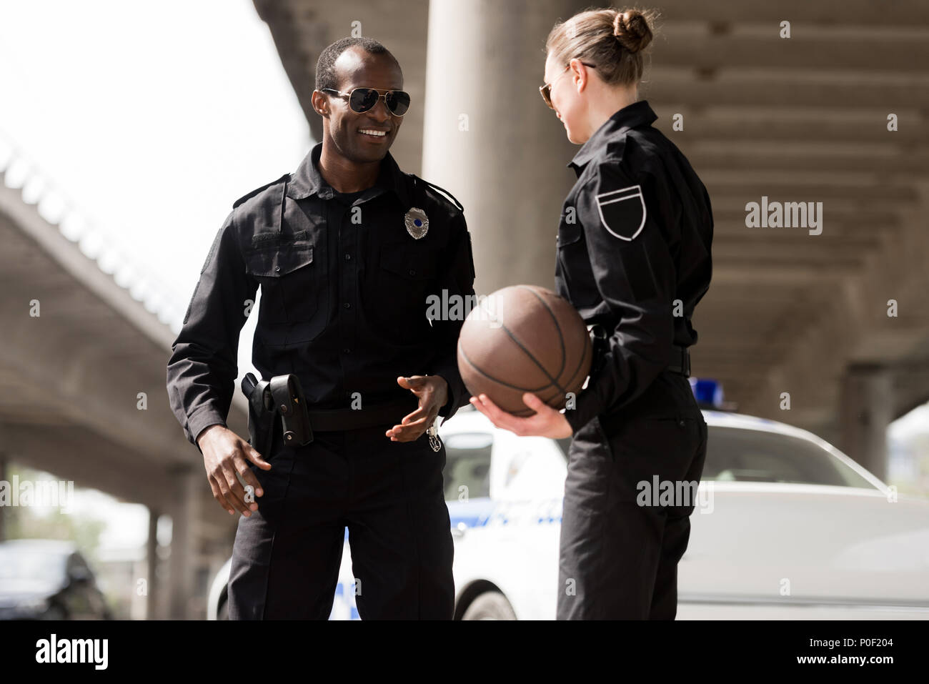 smiling young police officers with basketball ball Stock Photo