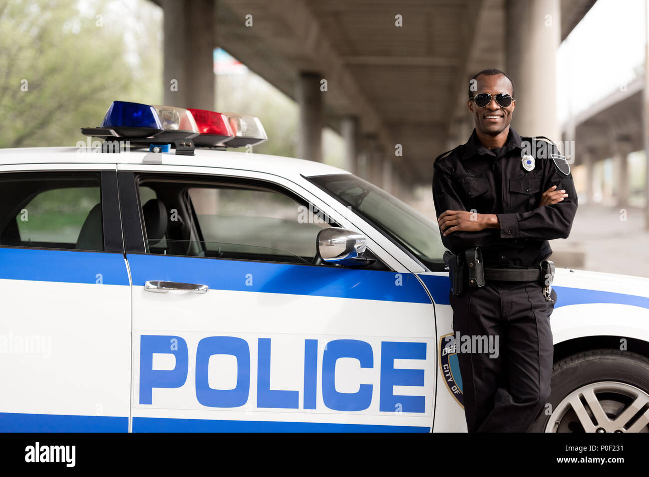 handsome african american police officer with crossed arms leaning back ...