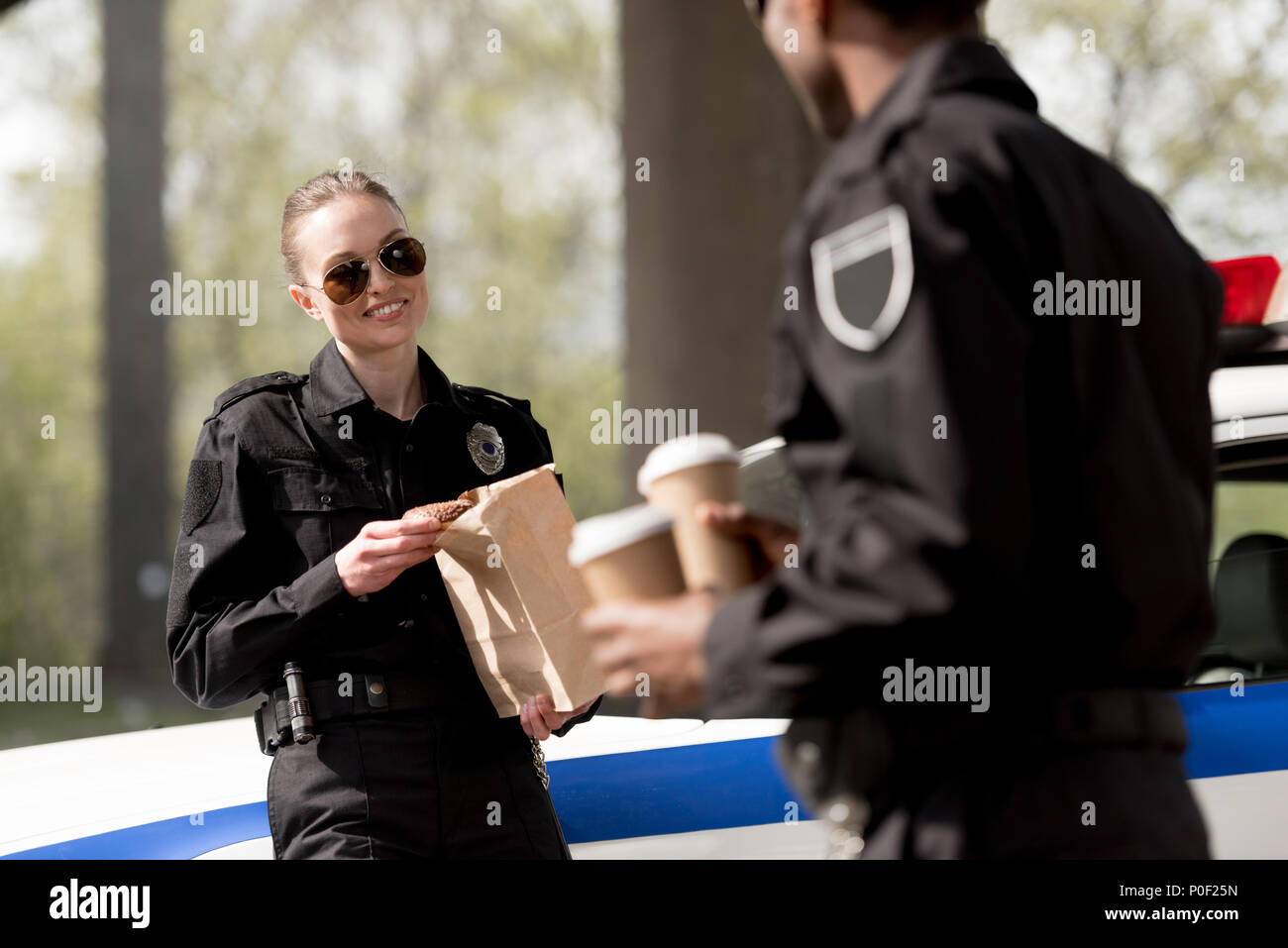 police officers with coffee to go and paper bag with lunch having break