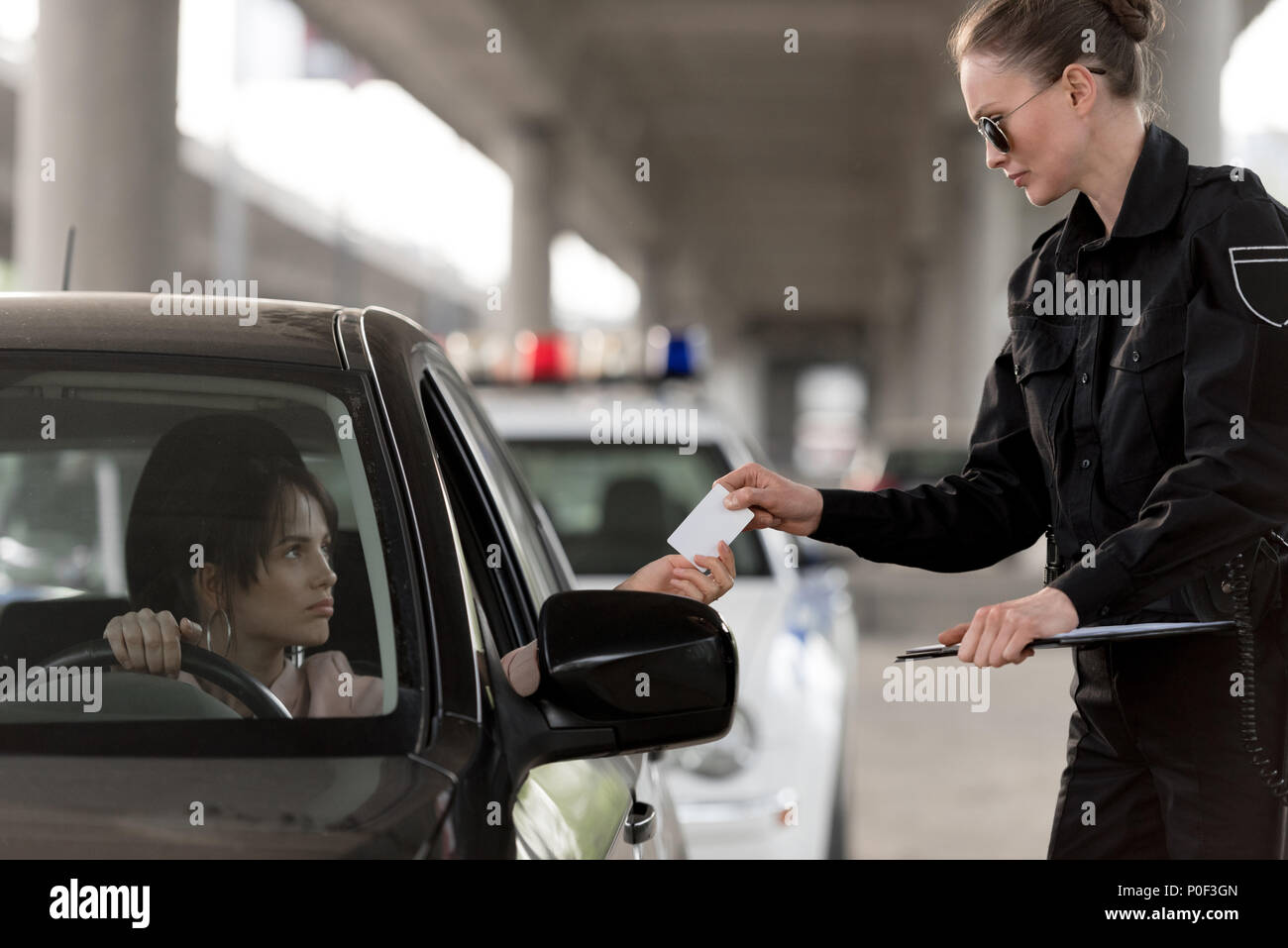 young woman in car giving driver license to policewoman in sunglasses Stock Photo