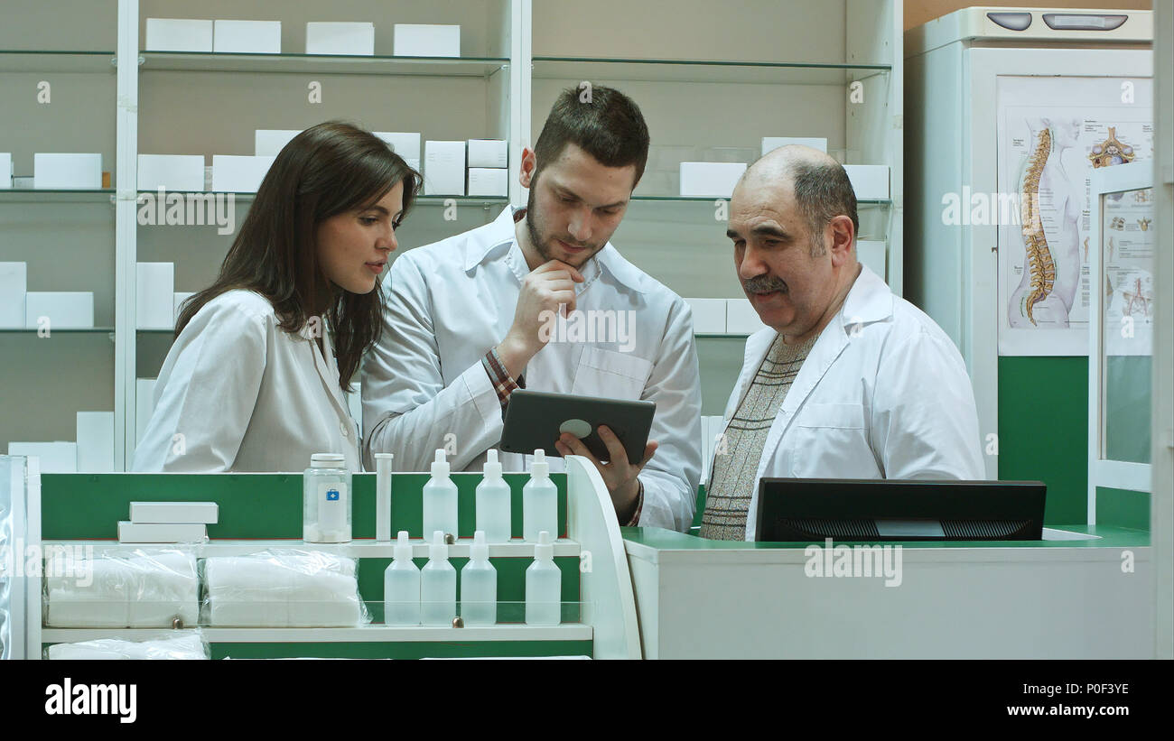 Three concentrated pharmacists using tablet computer at a counter in a pharmacy Stock Photo
