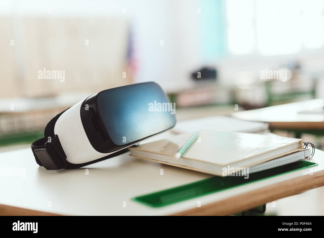 Closeup shot of virtual reality headset on table with textbook and pencil in classroom Stock Photo