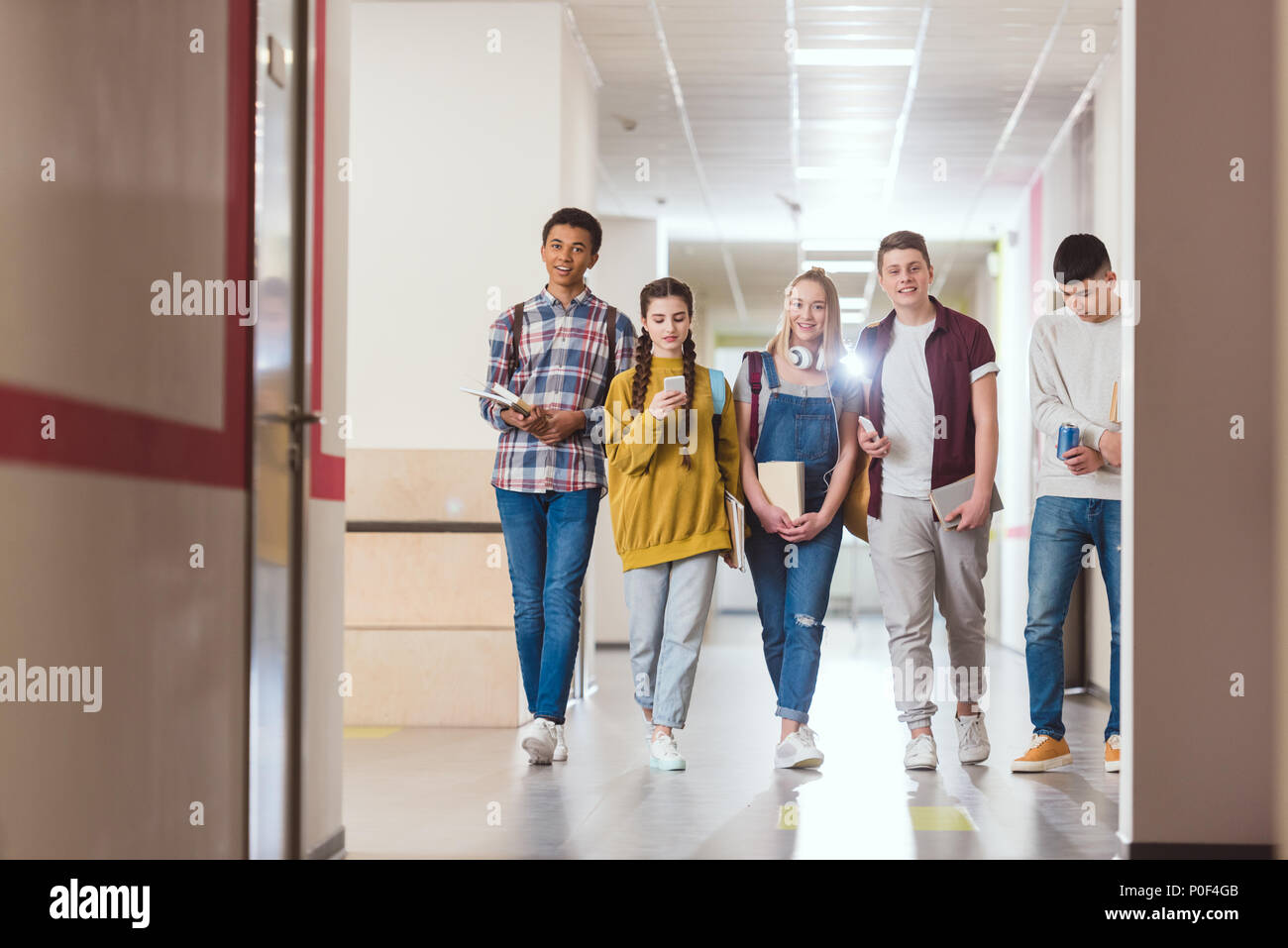 group of high school classmates walking by school corridor Stock Photo ...