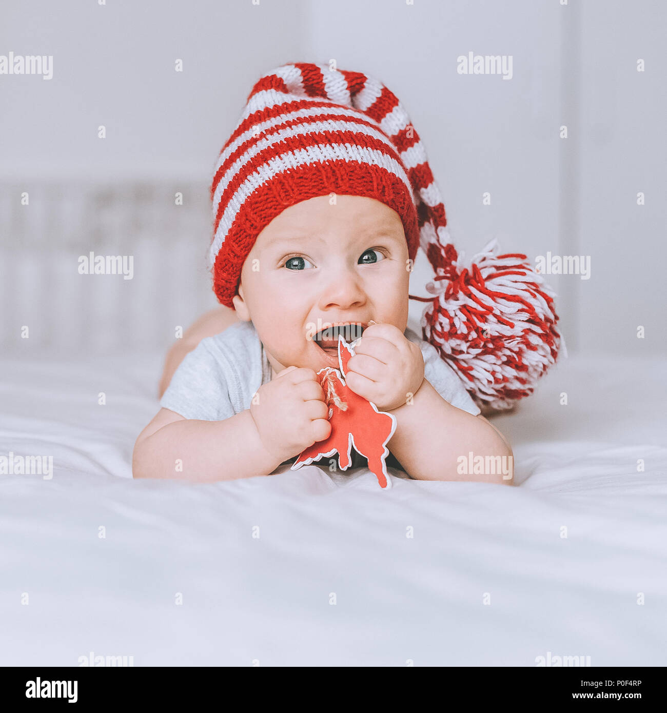 adorable infant child in red and white striped hat with pompom playing ...