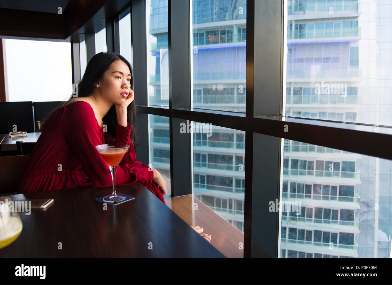 Pensive girl having a drink alone in a bar Stock Photo