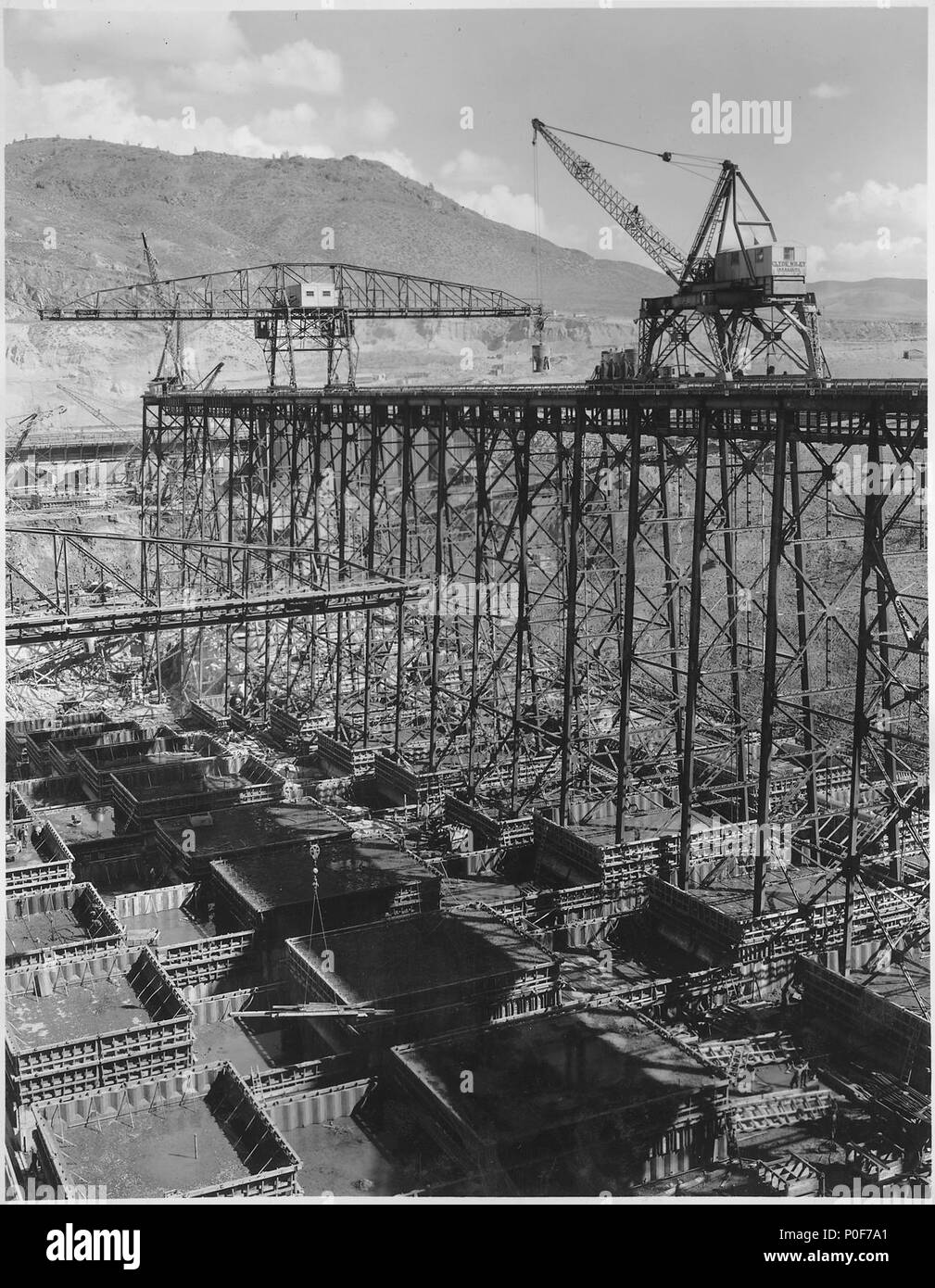 Upstream placing trestle on the west side showing cranes handling concrete blocks below. - Stock Photo