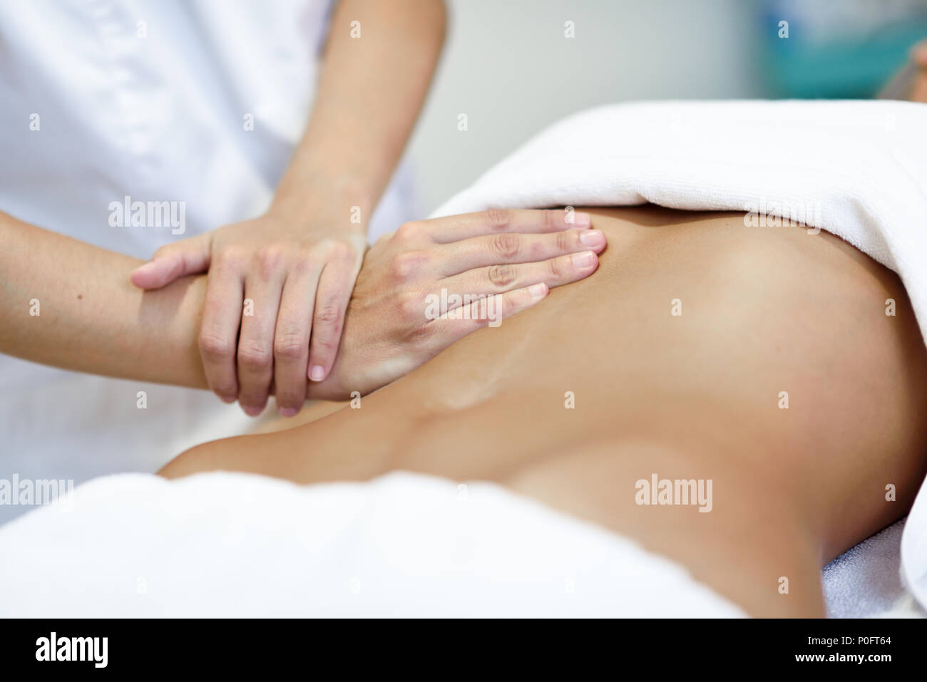 Hands massaging female abdomen.Therapist applying pressure on belly. Woman receiving massage at spa salon Stock Photo