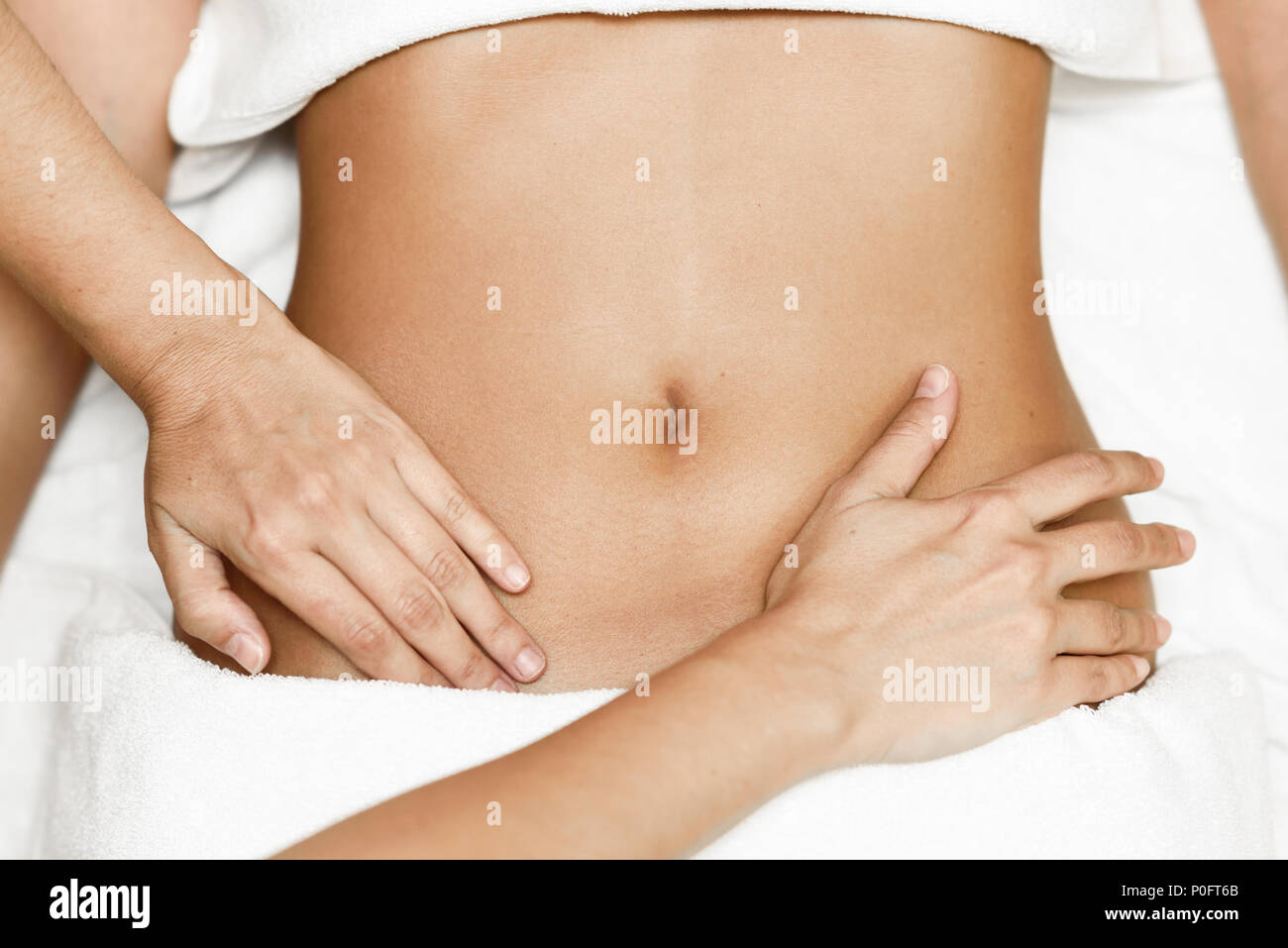 Top view of hands massaging female abdomen.Therapist applying pressure on belly. Woman receiving massage at spa salon Stock Photo