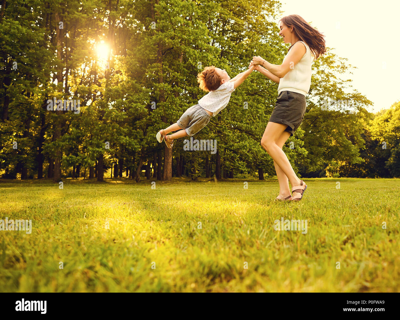 Mother with child playing in the park in summer at sunset Stock Photo ...