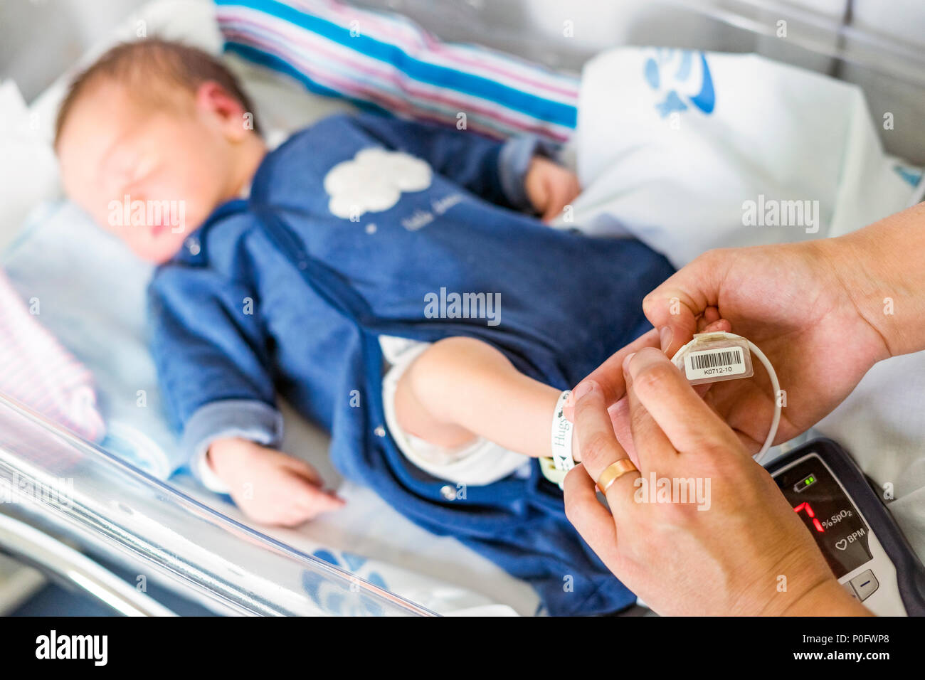 Using oximeter on newborn baby boy to check his level of oxygen in the hospital Stock Photo