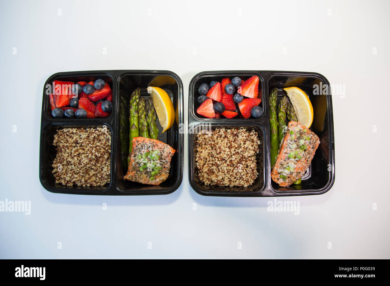 Planned meals in containers - salmon with asparagus, quinoa and fresh fruit. Stock Photo