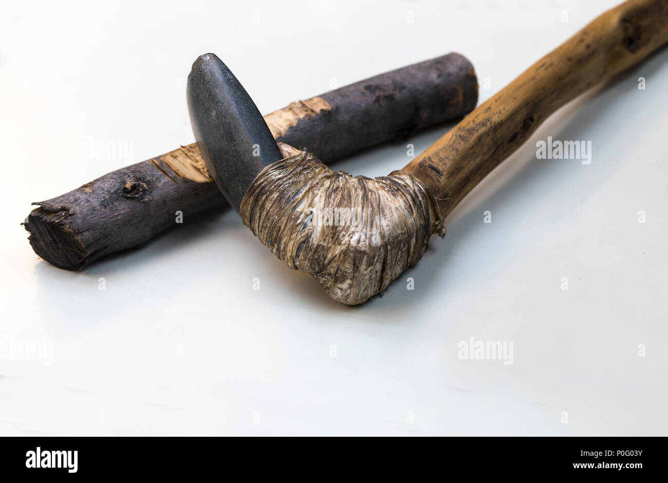 Agricultural lithic tool with wooden handle joint with tendon. Replica, Isolated over white background Stock Photo