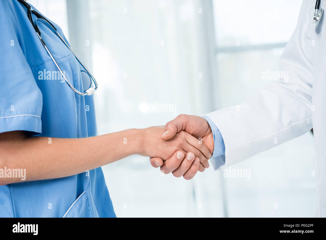 cropped shot of doctor and nurse with stethoscope shaking hands Stock ...
