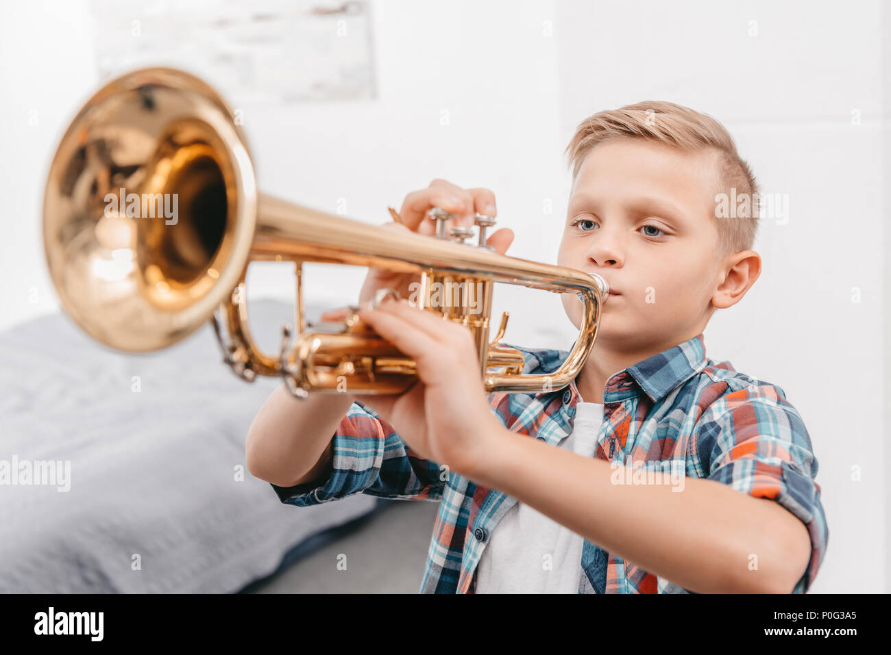 Young boy practicing playing trumpet in living room at home Stock