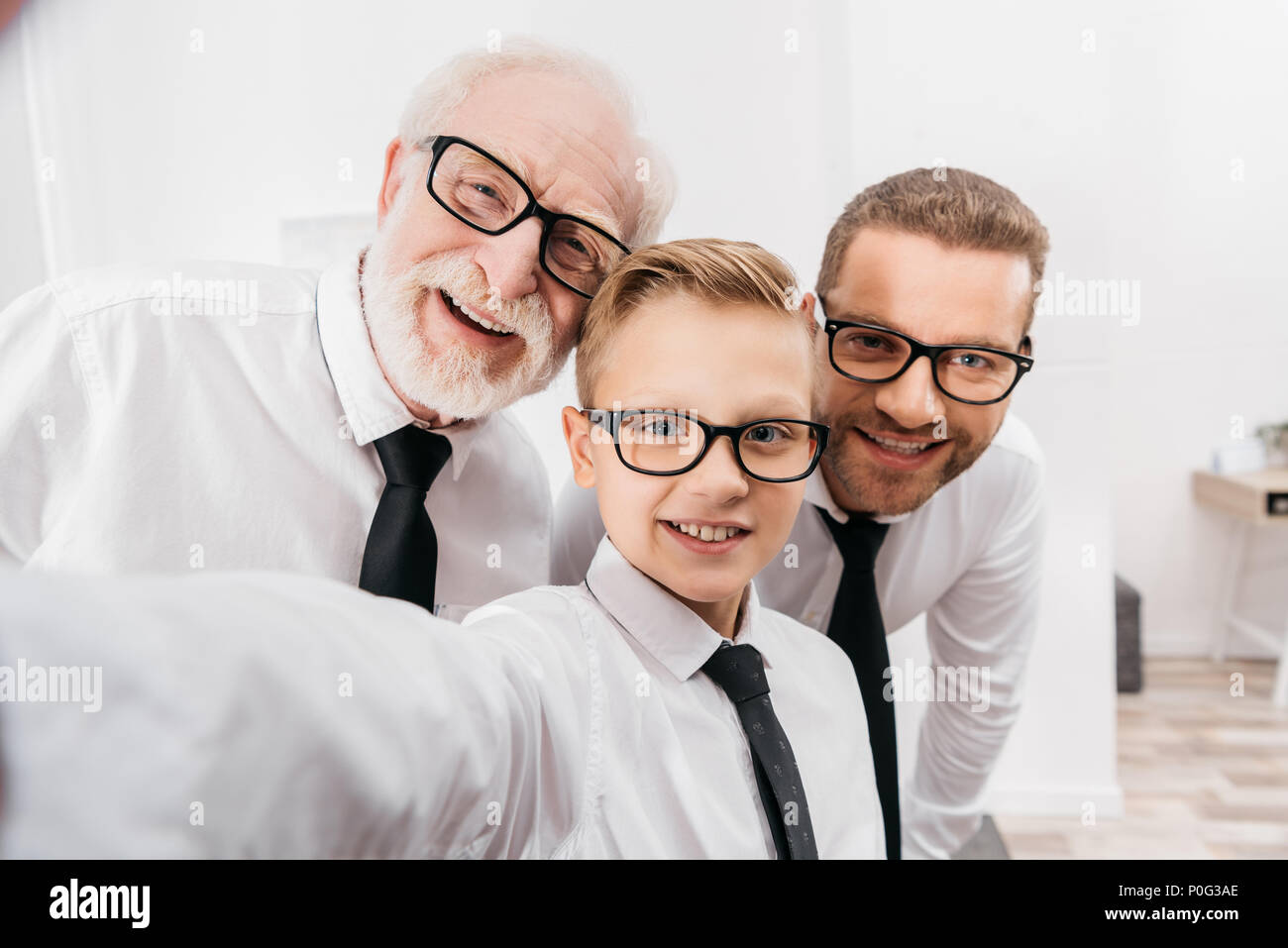 Father, son and grandfather wearing formal clothing and glasses taking a selfie Stock Photo