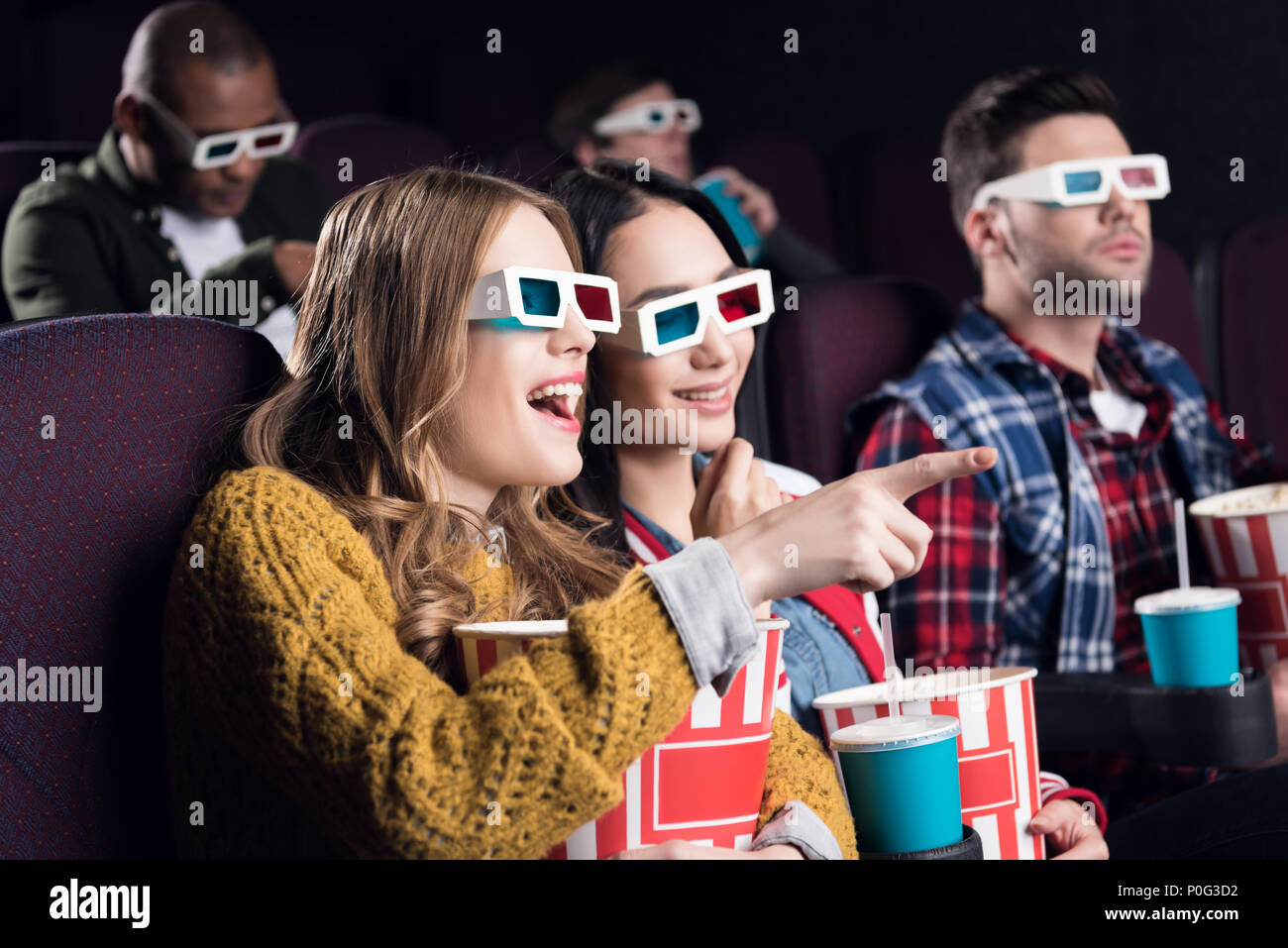 young smiling friends in 3d glasses with popcorn watching film in movie  theater Stock Photo - Alamy