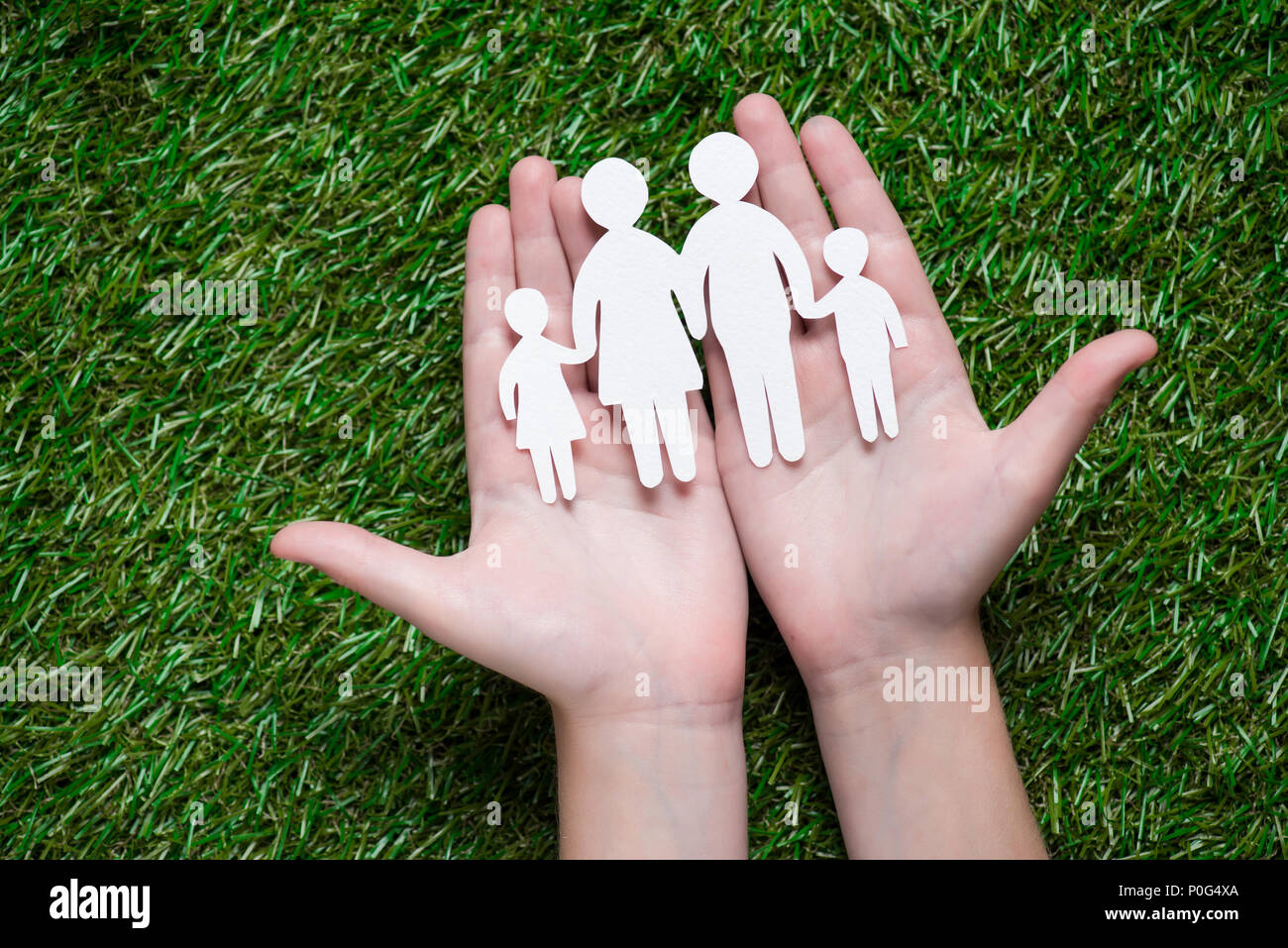 human hands holding paper cut of family on grass Stock Photo - Alamy