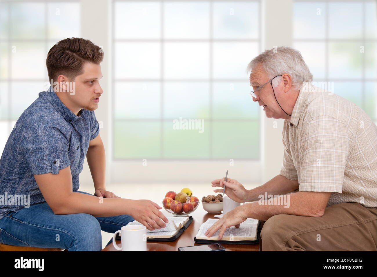 Church servant doing spiritual counseling to a young man studying the Bible Stock Photo