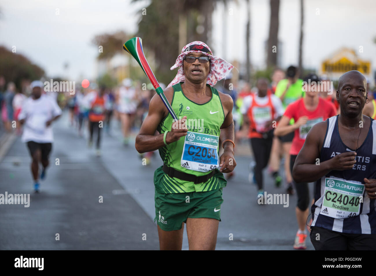 A runner carrying the vuvuzela instrument painted with the south African flag during the two oceans marathon Stock Photo