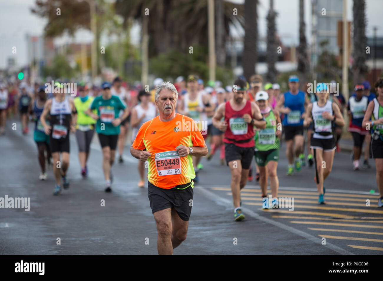 a runner looking tired during the two oceans marathon wearing a bright orange shirt Stock Photo