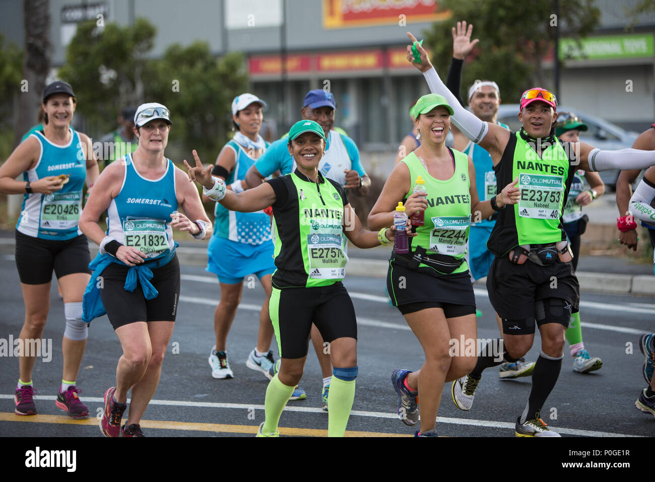 A group of runners smiling and waving at the camera during the two oceans ultra marathon in cape town Stock Photo