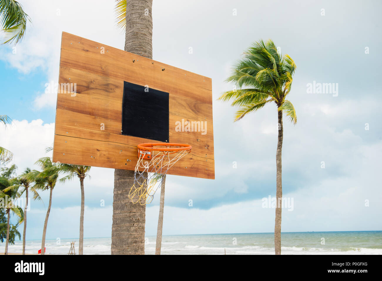 Basketball equipment on tropical island. Empty basket. Outdoor sport game. Active lifestyle in summer vacation. Streetball playing. Basketball in palm Stock Photo