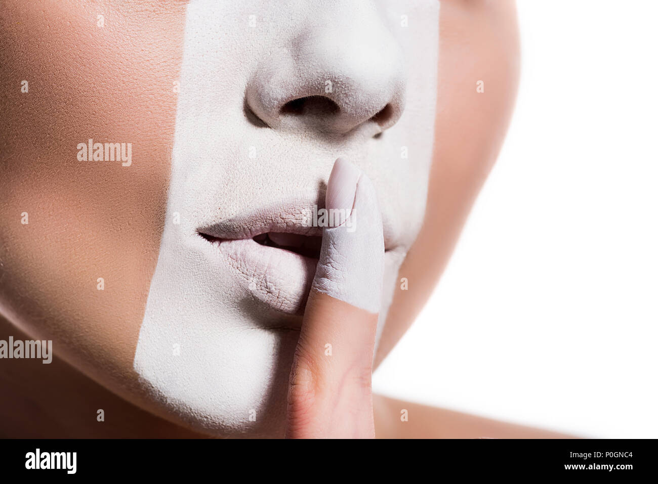 cropped image of woman with white paint on face showing silence sign isolated on white Stock Photo