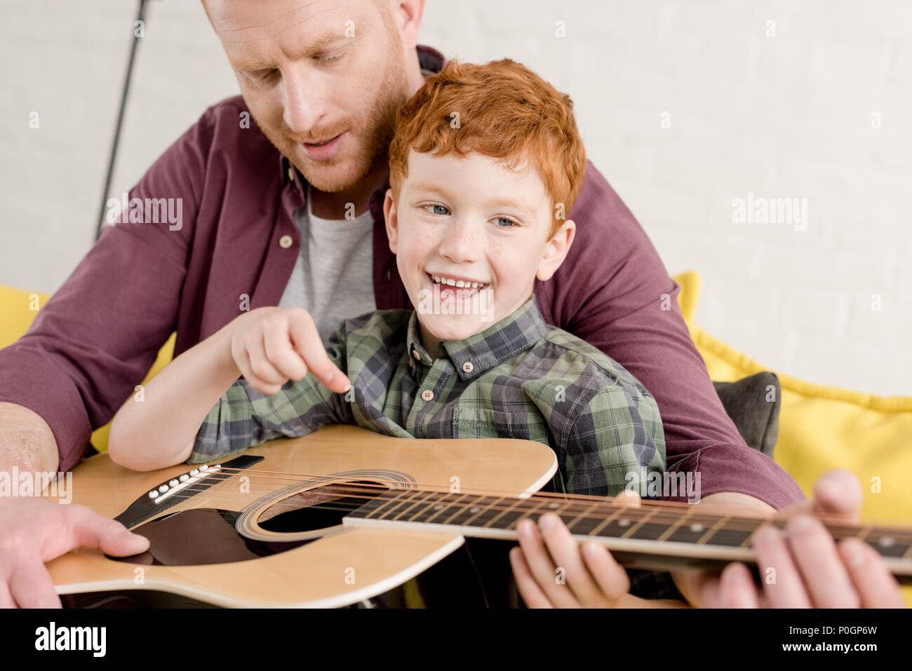 cropped shot of father teaching happy son playing guitar at home Stock Photo