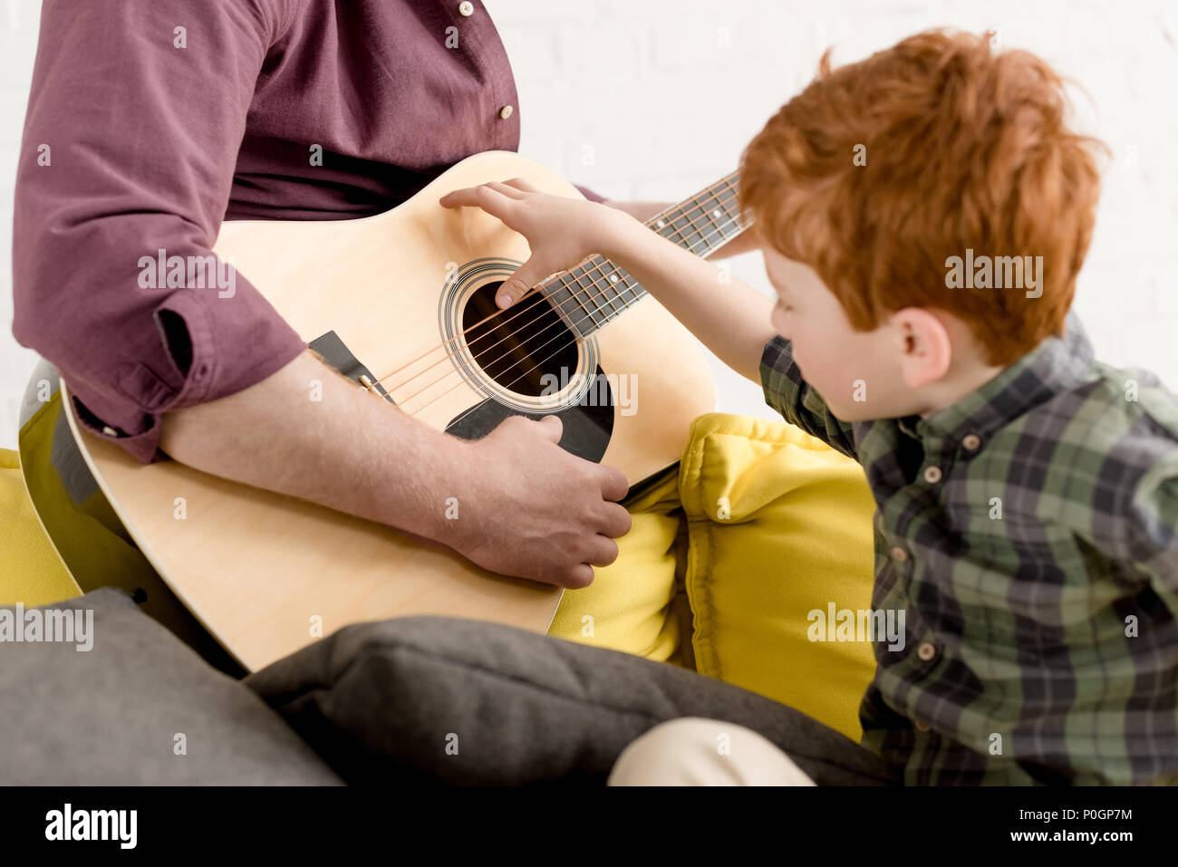 cropped shot of cute little boy looking at father playing guitar Stock Photo