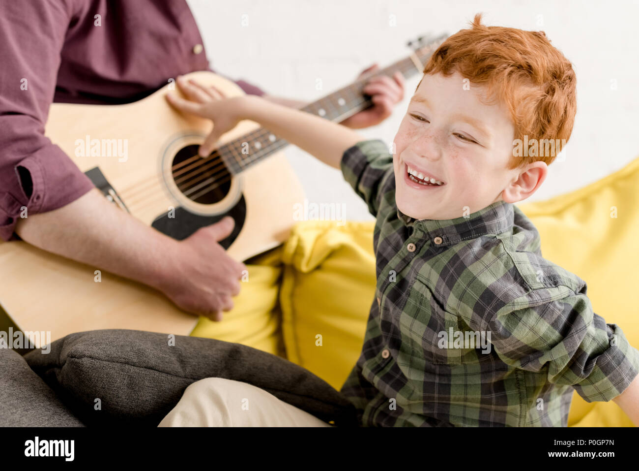 cropped shot of cute little boy laughing and father playing guitar Stock Photo