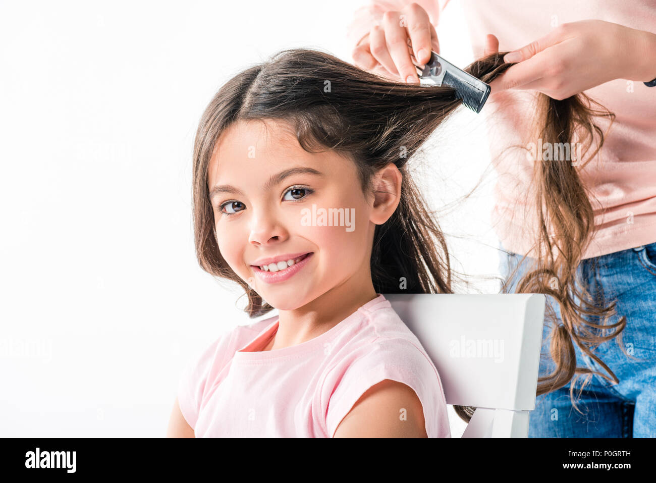 Cropped image of mother combing daughters hair isolated on white Stock Photo