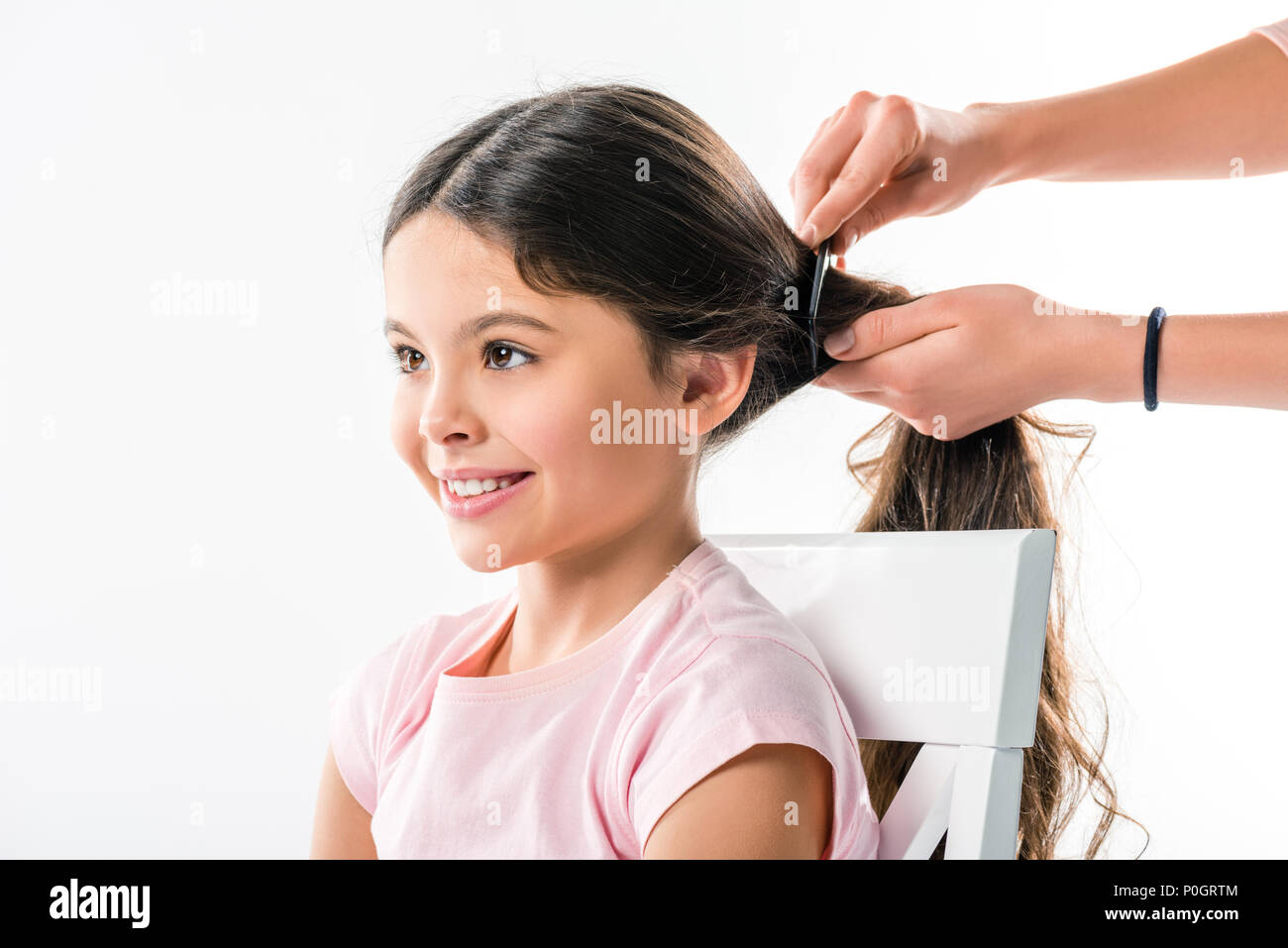 Cropped image of mother combing daughters hair with black comb isolated on white Stock Photo