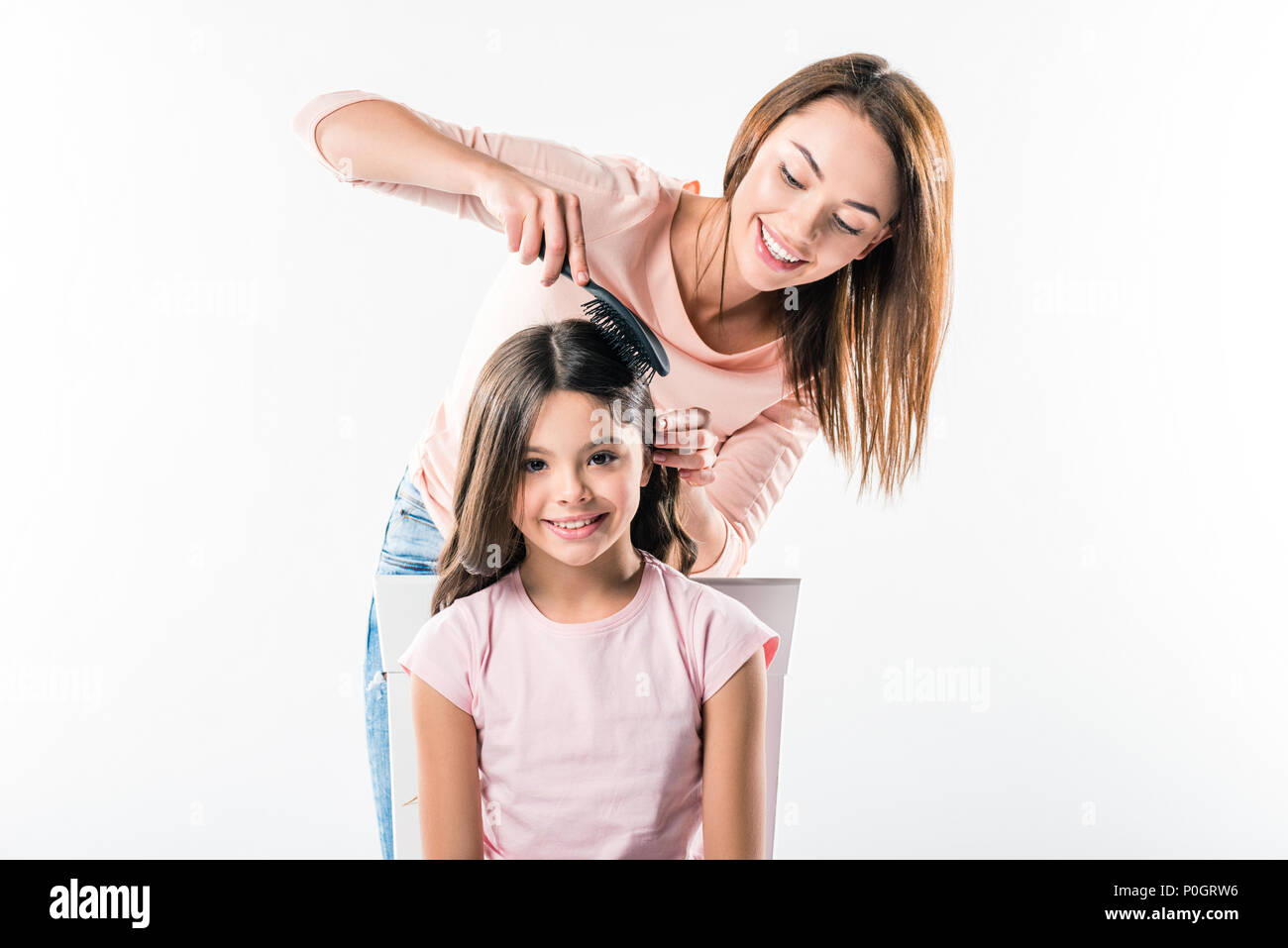 Mother combing daughters hair isolated on white Stock Photo