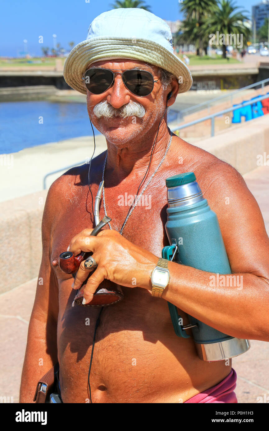 Local man standing with mate cup and thermos at the beach of Rio de la Plata in Montevideo, Uruguay. Mate is a traditional South American caffeine-ric Stock Photo