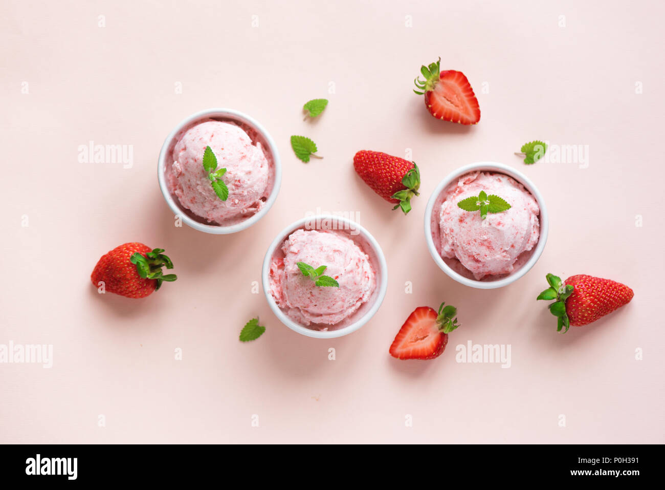 Strawberry ice cream and fresh strawberries flat lay on pink pastel background. Three bowls of