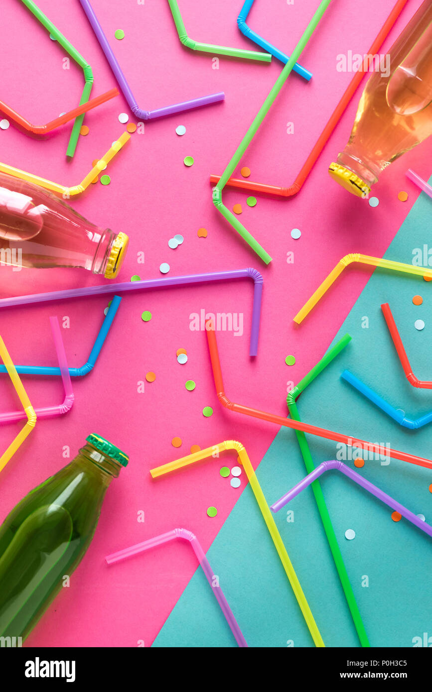 Various cold drinks with straws and confetti on pink and blue