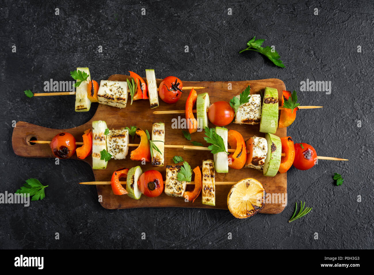 Vegetarian grilling. Vegetarian skewers with halloumi cheese and vegetables on black background, copy space. Stock Photo