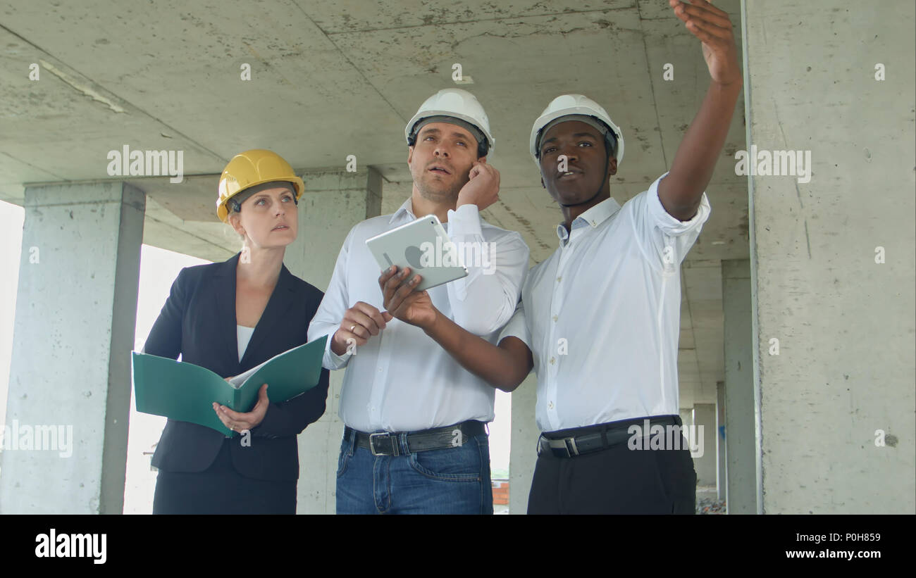 Executive team on construction site discussing project, using smartpone and digital tablet Stock Photo