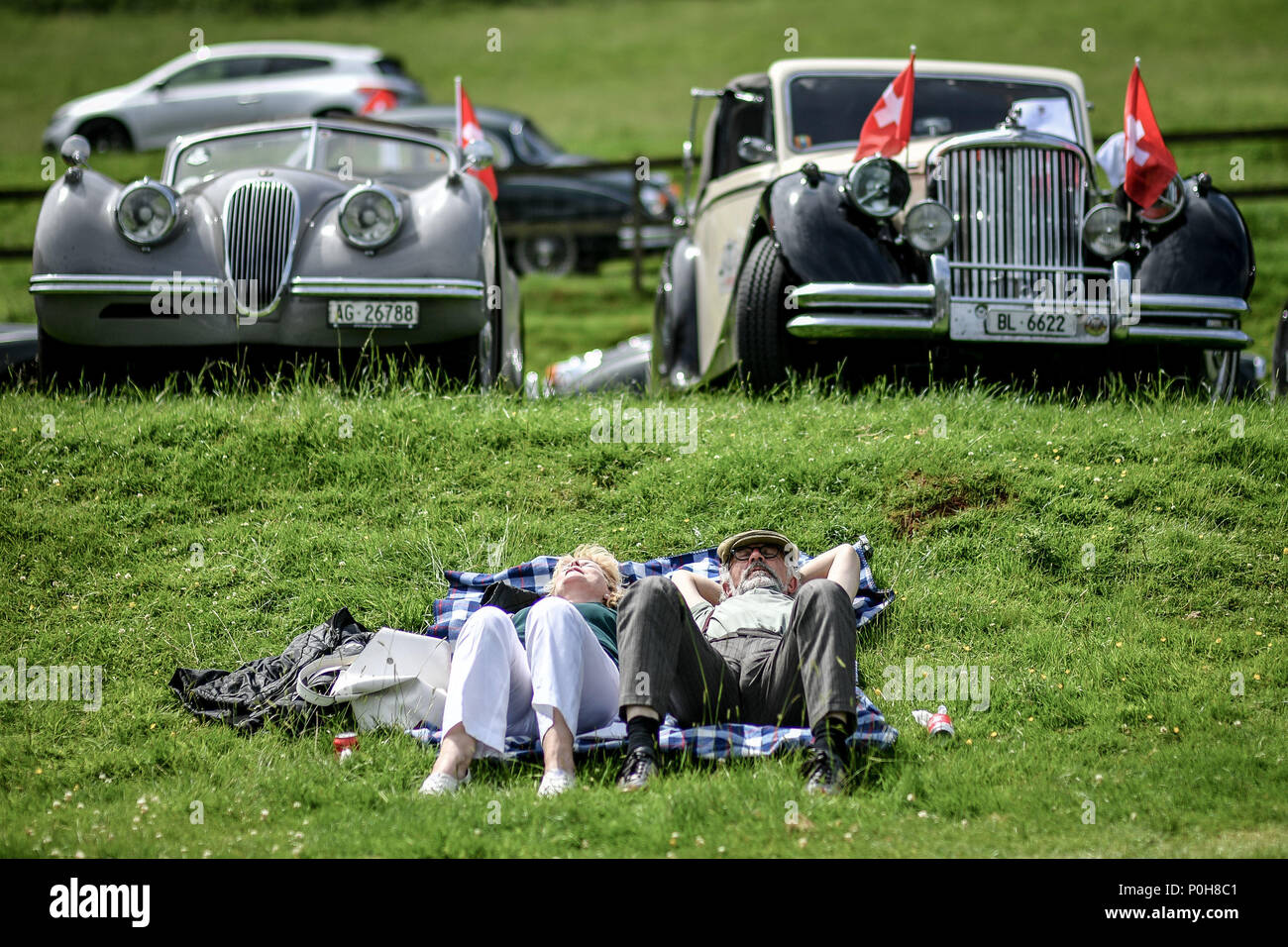 People relax by classic cars at the XK70 Jaguar Festival at Shelsley Walsh, Worcestershire, which is celebrating its 70th anniversary of the XK engine, which powered the vast majority of Jaguars produced between 1950 and 1986. Stock Photo