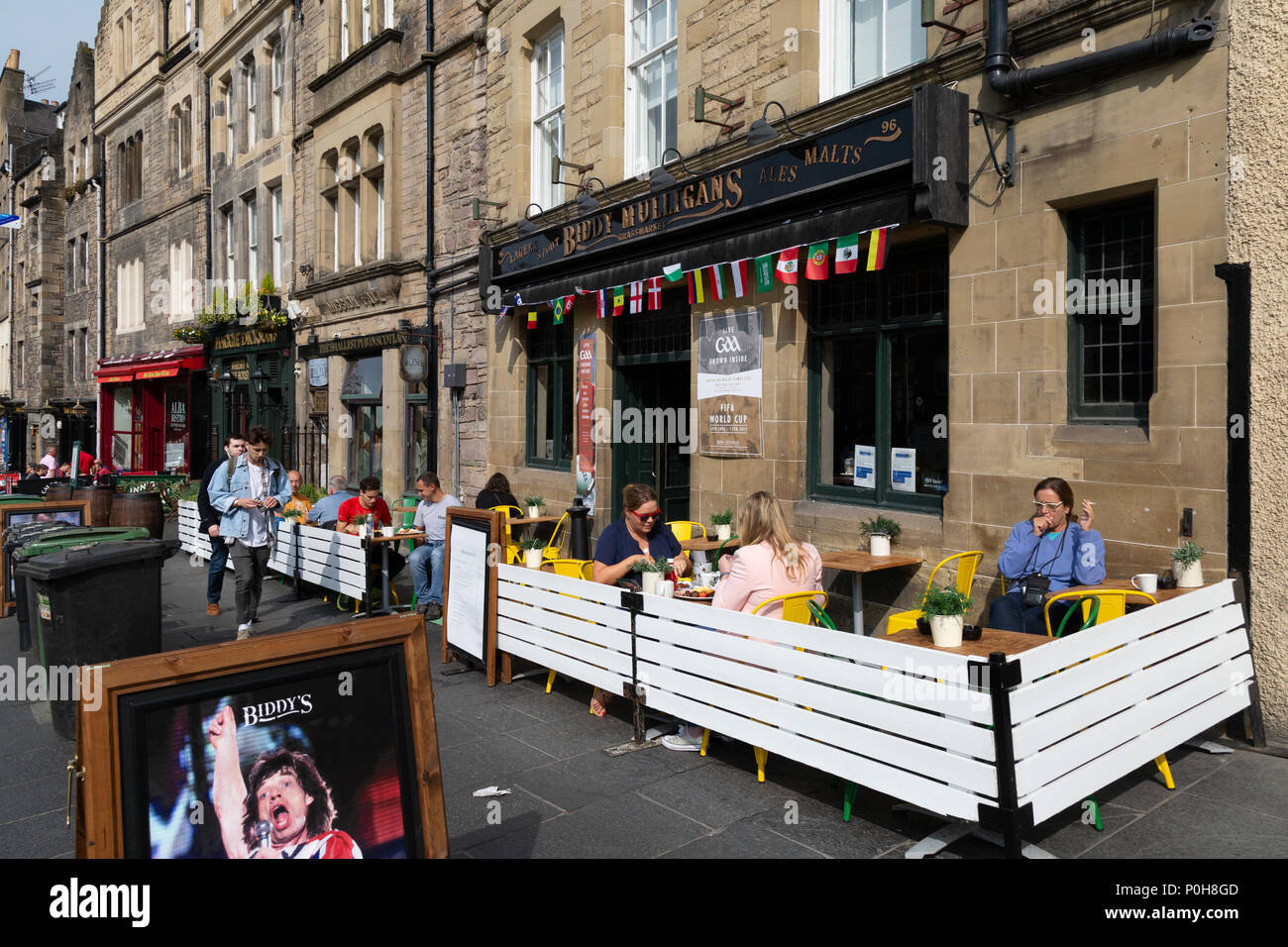People sitting in the sunshine outside Biddy Mulligans pub, Grassmarket, Edinburgh Old Town, Scotland UK Stock Photo