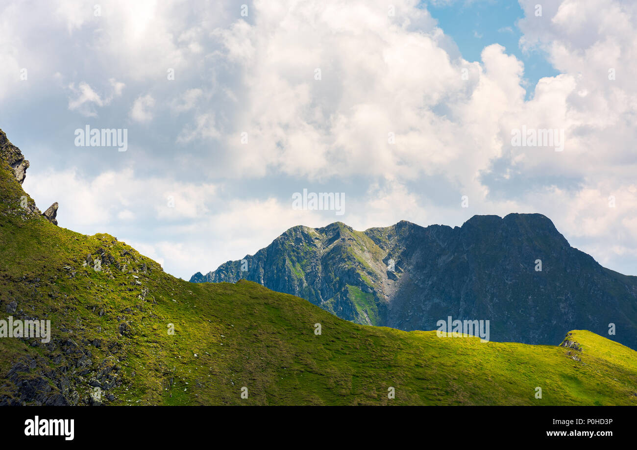 rocky ridge behind the grassy hill under the cloud. lovely mountainous scenery in summer Stock Photo