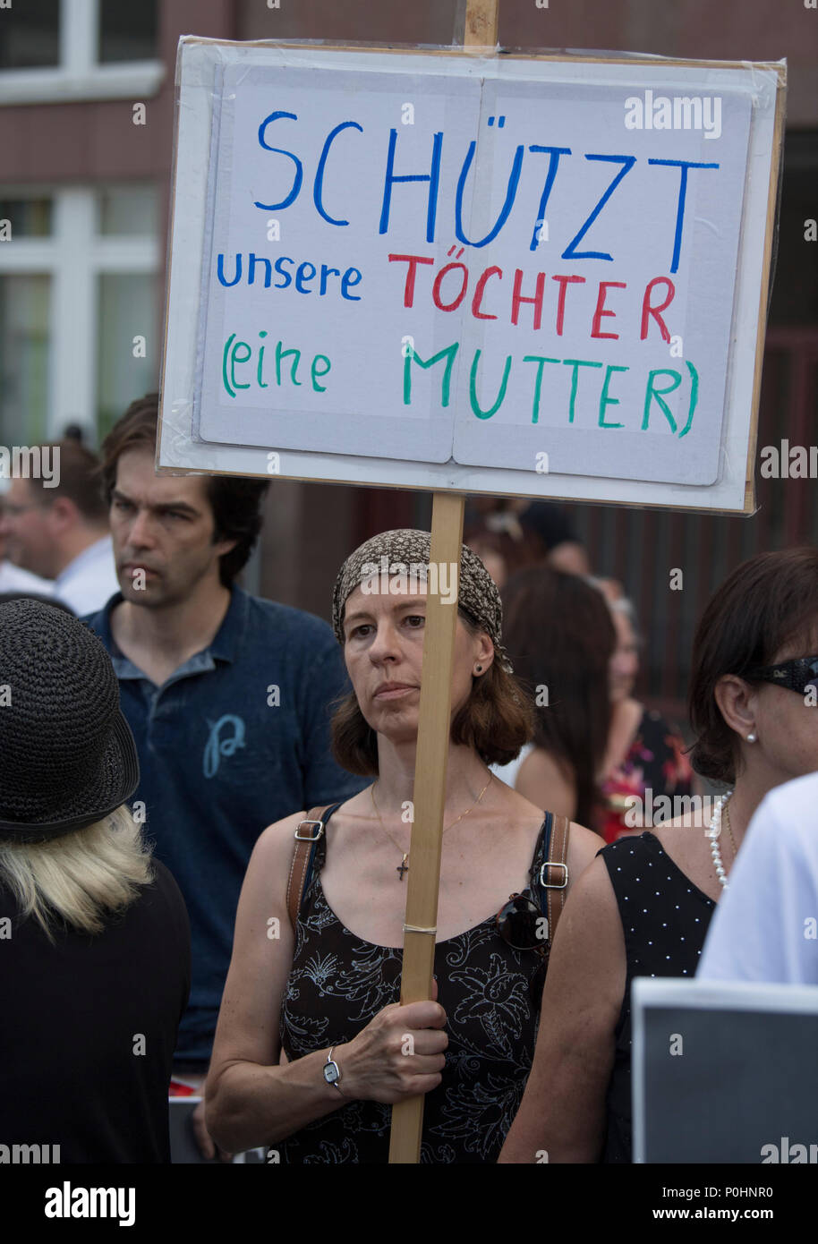 09 June 2018, Germany, Mainz: A few dozen people gather at a vigil organised by the Alternative for Germany (AfD) to commemorate 14-year-old murder victim Susanna. A woman carries a sign reading 'Schuetzt unsere Toechter (eine Mutter)' (lit. 'Protect our daughters (from a mother)'). An Iraqi refugee is suspected of having raped and murdered the girl. Photo: Boris Roessler/dpa Stock Photo