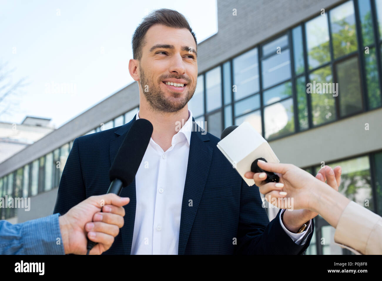 two journalists interviewing successful businessman with microphones Stock Photo
