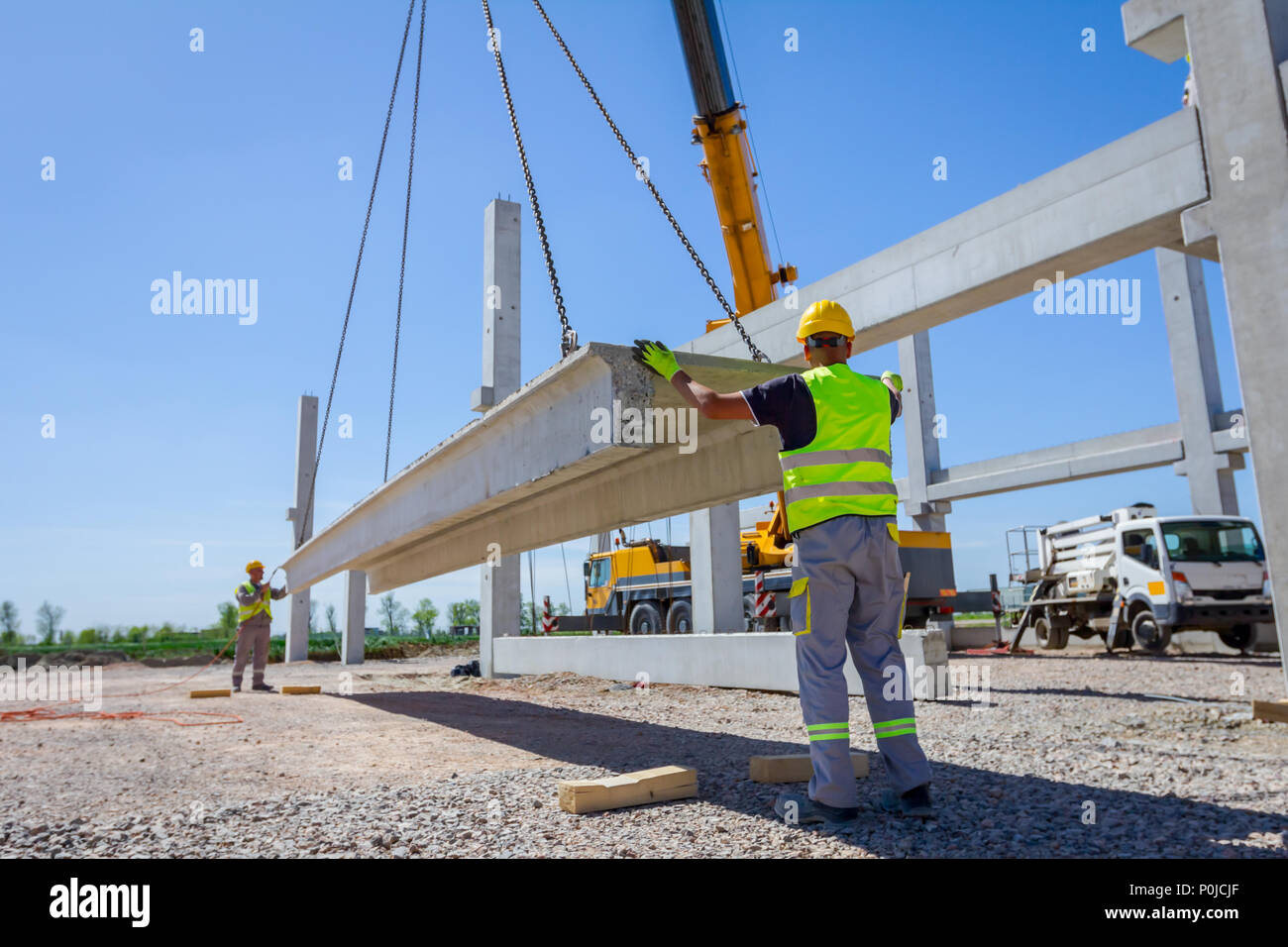 Workers are helping mobile crane to manage concrete joist for assembly ...