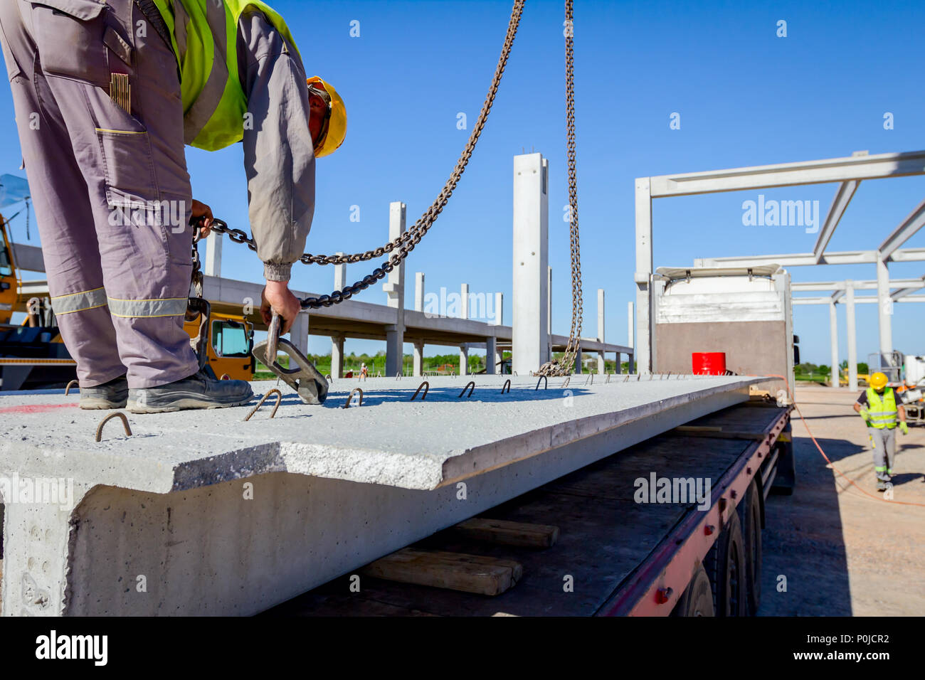 Unloading Hook Worker is preparing crane hook for unloading concrete joist from truck ...