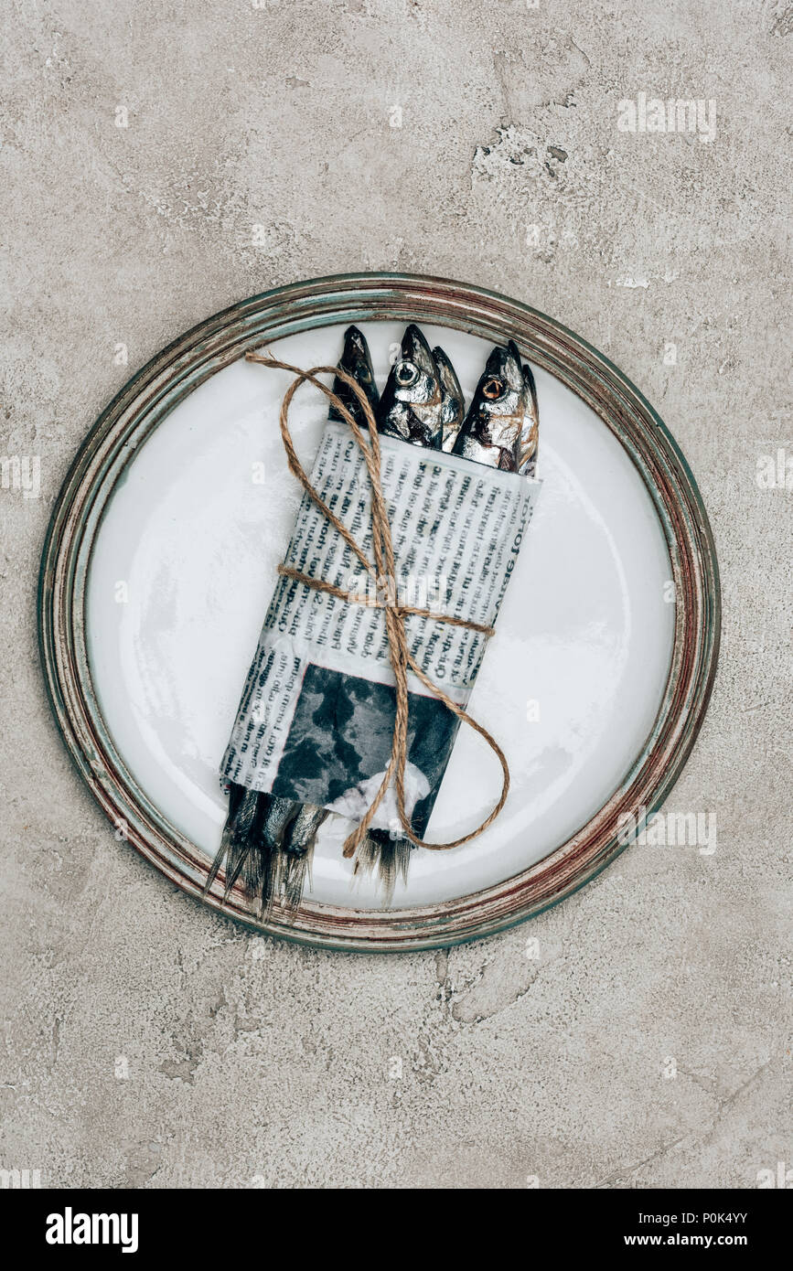 Pile of fish in newspaper wrapped by string on plate Stock Photo Alamy