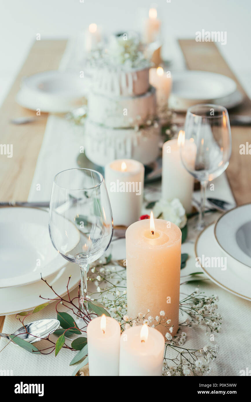 close up view of stylish table setting with candles, empty wineglasses