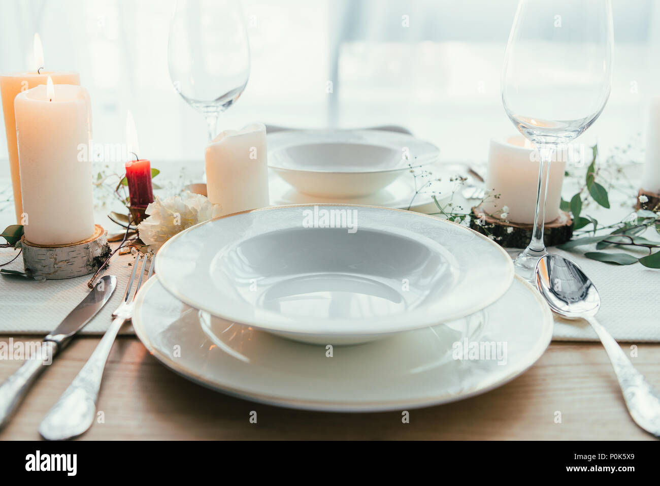 close up view of stylish table setting with candles, empty wineglasses