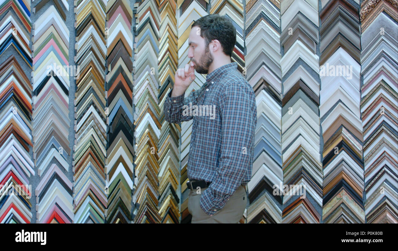 Young male customer looking for a frame for his picture in atelier Stock Photo