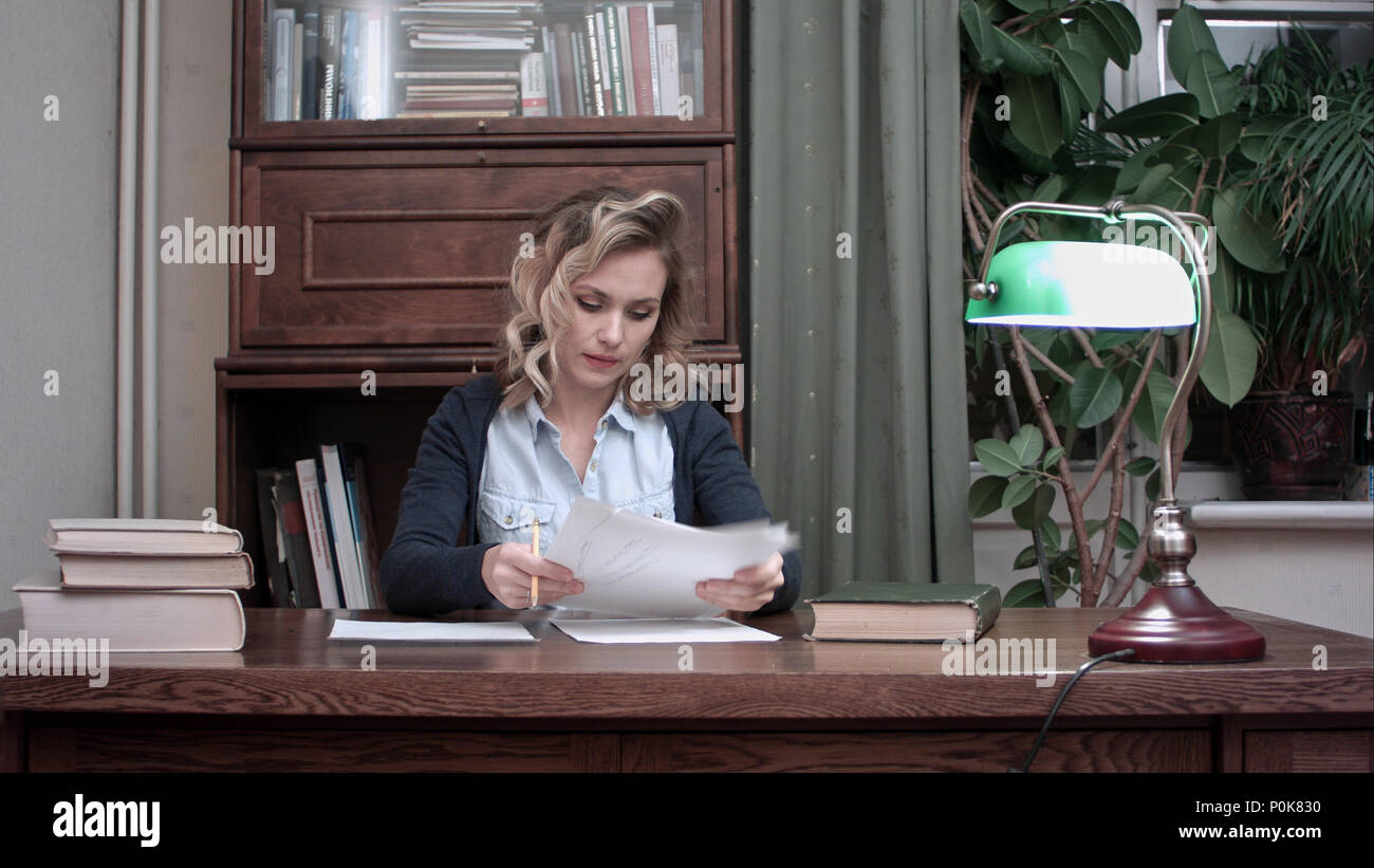 Young woman going through papers and making notes Stock Photo
